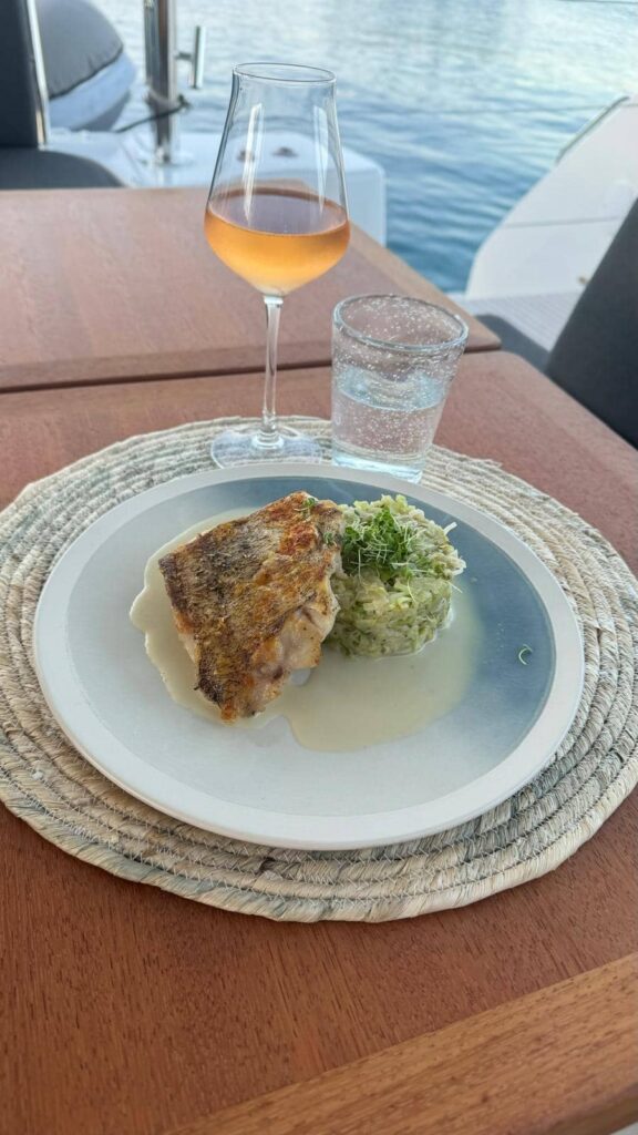 assiette gastronomique accompagnée d'un verre de vin sur le pont du catamaran épicure sailing